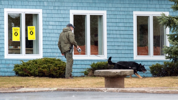 An RCMP officer and his dog search the exterior of the Assumption Parish Centre in Stratford, P.E.I.
