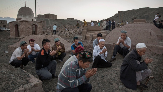 TURPAN, CHINA - SEPTEMBER 11: (CHINA OUT) Uyghur men perform prayers for ancestors at a cemetery before the Corban Festival on September 11, 2016 in Turpan County, in the far western Xinjiang province, China. The Corban festival, known to Muslims worldwide as Eid al-Adha or 'feast of the sacrifice', is celebrated by ethnic Uyghurs across Xinjiang, the far-western region of China bordering Central Asia that is home to roughly half of the country's 23 million Muslims. The festival, considered the most important of the year, involves religious rites and visits to the graves of relatives, as well as sharing meals with family. Although Islam is a 'recognized' religion in the constitution of officially atheist China, ethnic Uyghurs are subjected to restrictions on religious and cultural practices that are imposed by China's Communist Party. Ethnic tensions have fueled violence that Chinese authorities point to as justification for the restrictions. (Photo by Kevin Frayer/Getty Images)