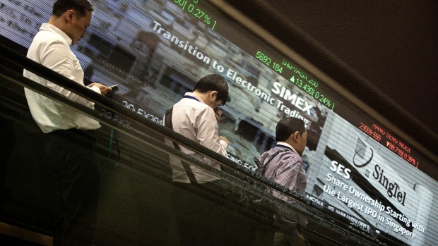 Men ride on an escalator past an electronic screen and ticker board displaying stock figures at the Singapore Exchange Ltd. (SGX) headquarters in Singapore, on Thursday, Jan. 19, 2017. The SGX has tendered a 4.75% stake in the Bombay Stock Exchange for sale in an initial public offer, valuing its shares at S$42.8m to S$42.9m, the exchange said in a filing today. 
