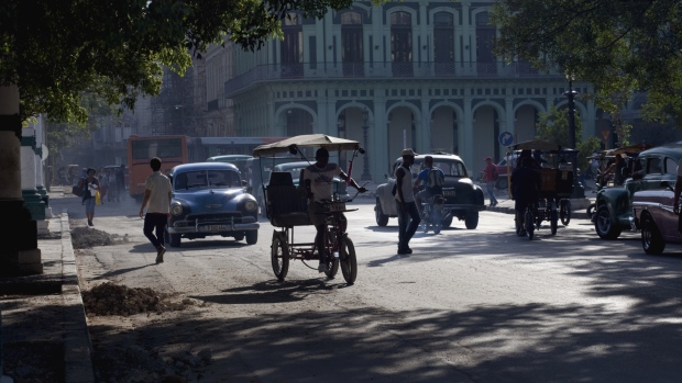 People and vehicles cross a street in Havana. Photographer: Eliana Aponte/Bloomberg