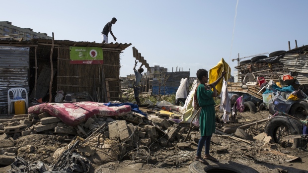 Men work to repair the damaged roof of a small shop while a woman hangs clothing to dry amongst debris from damaged buildings following the cyclone in Beira, Mozambique, on Thursday, March 28, 2019.