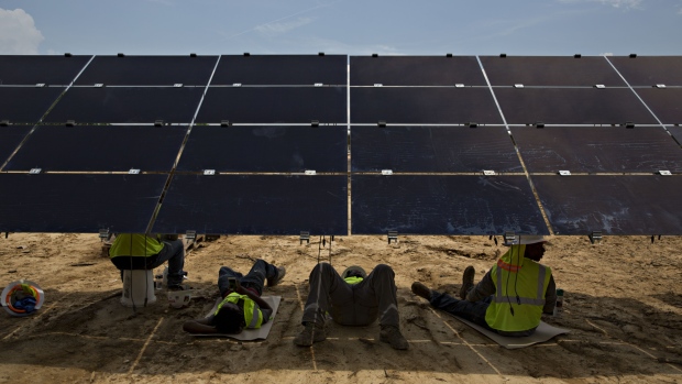 Workers take a break in the shade of a solar panel during construction of a Silicon Ranch Corp. solar generating facility in Milligan, Tennessee, U.S., on Thursday, May 24, 2018. Large oil companies in Europe are continuing to diversify their holdings and increase clean-energy investments. Royal Dutch Shell Plc agreed in January to buy a 44 percent stake in Silicon Ranch Corp., the Nashville-based owner and operator of U.S. solar plants. 