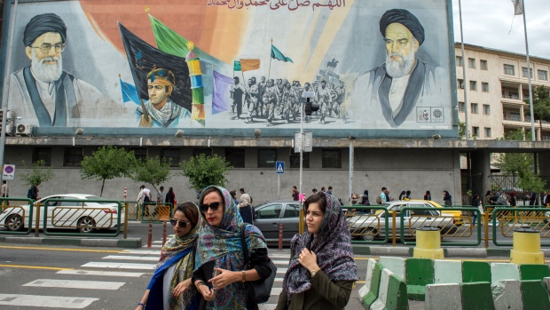 Women cross a street near a giant political mural depicting Ayatollah Ali Khamenei, Iran's supreme leader, left, and Ruhollah Khomeini, founder of the Islamic republic of Iran, in Tehran, Iran, on Wednesday, May 9, 2018.