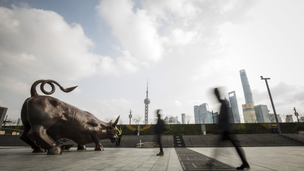 Pedestrians walk past the Bund Bull statue as skyscrapers of the Pudong Lujiazui Financial District stand across the Huangpu River in Shanghai, China, on Friday, Dec. 28, 2018. China announced plans to rein in the expansion of lending by the nation's regional banks to areas beyond their home bases, the latest step policy makers have taken to defend against financial risk in the world's second-biggest economy. 