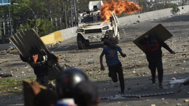 Flames and smoke rise from an armored vehicle during clashes between protesters and members of the National Bolivarian Armed Forces after an attempted military uprising on Francisco Fajardo Highway in Altamira, Caracas, Venezuela, on Wednesday, May 1, 2019. One day after an attempt to spark a military uprising fell flat, Venezuela's opposition was at it again Wednesday, making another desperate effort to rally residents to oust President Nicolas Maduro. 