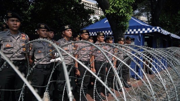 Members of the Indonesian National Police stand guard in front of barbed wire outside the General Election Commission in Jakarta on May 15, 2019. 