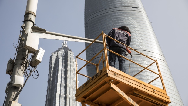 A man stands on an elevated platform while performing maintenance work on a surveillance camera in front of the Shanghai Tower, right, and the Jin Mao Tower in the Lujiazui Financial District in Shanghai, China, on Monday, Feb. 26, 2018. Xi Jinping's decision to cast aside China's presidential term limits is stoking concern he also intends to shun international rules on trade and finance, even as he champions them on the world stage. 