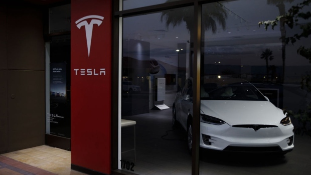 Pedestrians walk past a closed Tesla Inc. store in Palm Desert, California, U.S., on Thursday, March 7, 2019. Tesla has cut prices of the Model 3 and its other vehicles several times this year to offset the lower incentives, most recently by announcing a plan to close most stores and shift all ordering online. 