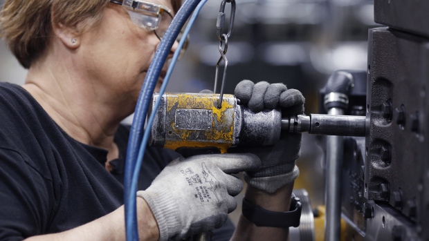 A factory worker uses a power drill to assemble components on a diesel engine in Seymour, Indiana. 