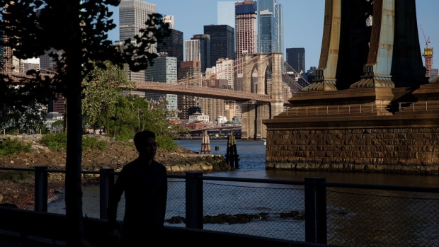 A pedestrian walks along the waterfront in Main Street Park in the Brooklyn borough of New York, U.S., on Wednesday, May 22, 2019. Stocks slumped globally on Thursday and traders took refuge in gold and bonds as the simmering trade dispute between the world's two largest economies took a greater toll on markets. 