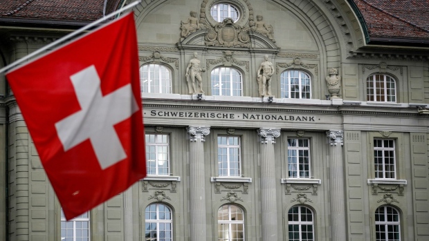 A Swiss national flag hangs in view of the Swiss National Bank (SNB) in Bern, Switzerland, on Friday, April 26, 2019. The Swiss National Bank is in no position to raise interest rates given markets are still in a "fragile" state, according to President Thomas Jordan. 