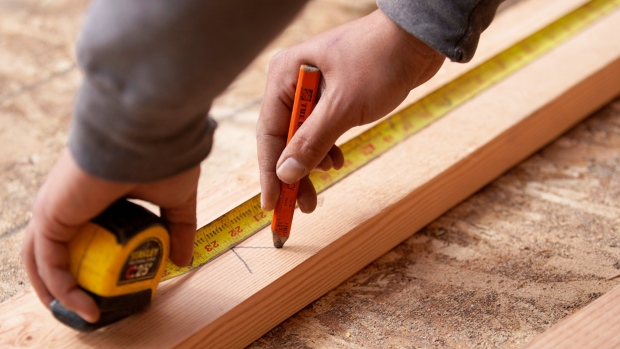 A worker uses a tape measure to mark lumber at a home under construction in Vineyard, Utah, U.S., on Tuesday, March 12, 2019. The National Association of Home Builders (NAHB) released housing market index figures on March 18. 