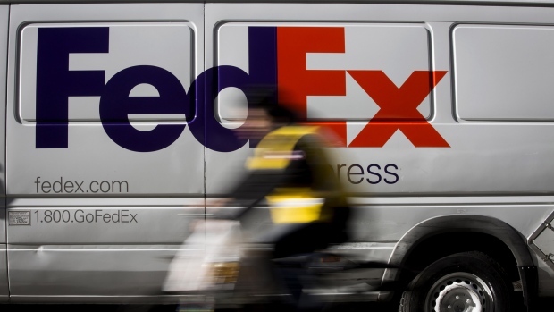 A bicyclist rides past a FedEx Corp. vehicle parked in the Midtown neighborhood of New York. 