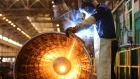A worker uses a hand welding machine while working on a steel pipe at a mill. 