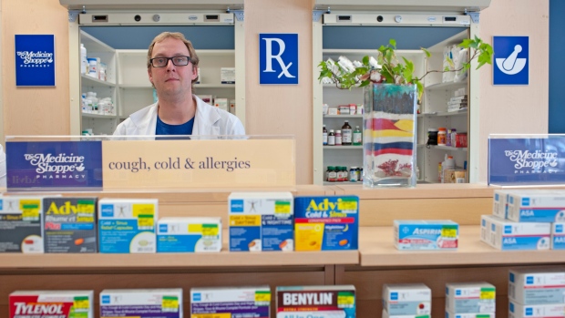 Matthew Manz, left, stands behind the counter at the pharmacy he manages in Regina, Sask., May 31, 2