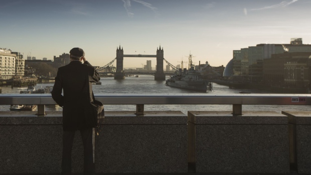 A commuter stops on London Bridge to view Tower Bridge in the distance in London, U.K., on Monday, Dec. 18, 2017. U.K. firms wanting workers face the tightest labor market in two decades. In 2011, there were almost six unemployed people for every vacancy; now there are fewer than two, the lowest ratio since records began in 2001. 