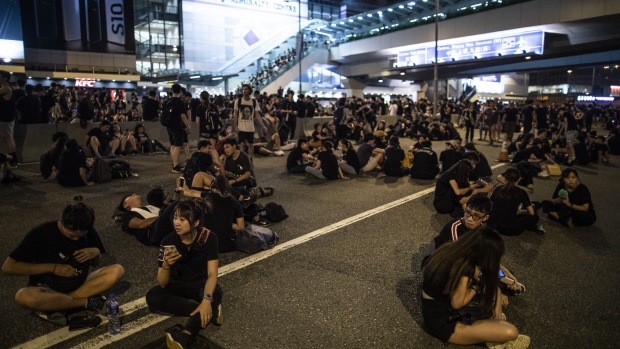 Police officers stand guard as protesters march past the Police Headquarters during a rally in Hong Kong, China, on Sunday, June 16, 2019. Tens of thousands of demonstrators poured into central Hong Kong as organizers remained defiant even after the city's leader suspended consideration of the China-backed extradition plan that sparked some of the biggest protests in the city in decades. Photographer: Giulia Marchi/Bloomberg