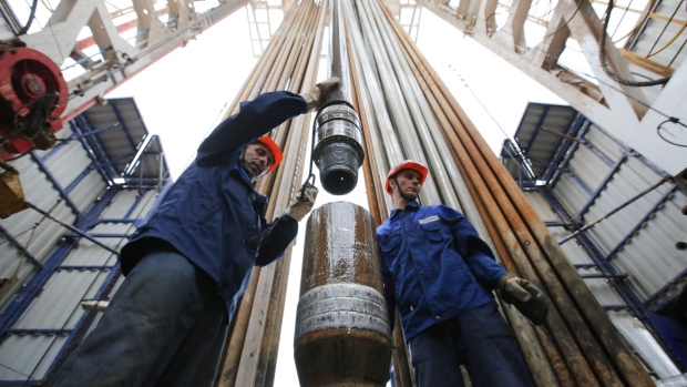Workers secure drilling pipe sections on an oil drilling tower operated by Tatneft OAO near Almetyevsk, Russia, on Friday, July 31, 2015. 