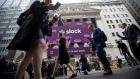 Pedestrians pass in front of a Slack Technologies Inc. signage displayed outside of the New York Stock Exchange during the company's initial public offering in New York on June 20, 2019. 