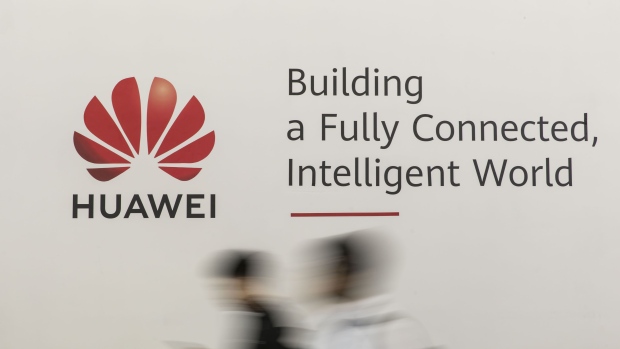 Attendees walk past signage for Huawei Technologies Co. at the MWC Shanghai exhibition in Shanghai, China, on Thursday, June 27, 2019. The Shanghai event is modeled after a bigger annual industry show in Barcelona. 