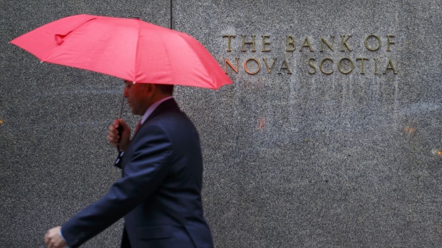 A pedestrian carrying an umbrella walks past the Bank of Nova Scotia headquarters building in Toronto, Ontario, Canada, on Tuesday, April 4, 2017. Scotiabank heads have said that the government may have to impose more measures to cool Toronto's housing market if prices remain "overheated" after the spring buying season. 