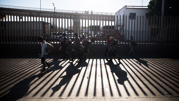 Central American migrants walk along a fence near the U.S. and Mexico border in Tijuana, Mexico. 