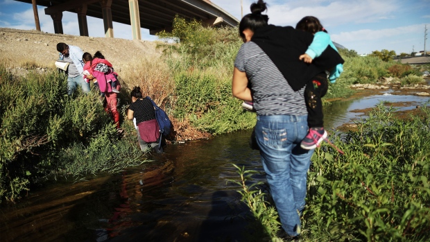 CIUDAD JUAREZ, MEXICO - MAY 19: Migrants cross the border between the U.S. and Mexico at the Rio Grande river, as they walk to enter El Paso, Texas, on May 19, 2019 as taken from Ciudad Juarez, Mexico. The location is in an area where migrants frequently turn themselves in and ask for asylum in the U.S. after crossing the border. Approximately 1,000 migrants per day are being released by authorities in the El Paso sector of the U.S.-Mexico border amidst a surge in asylum seekers arriving at the Southern border. (Photo by Mario Tama/Getty Images)