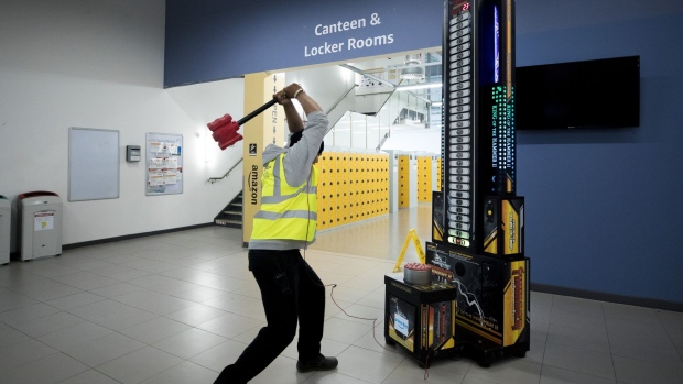 An employee hits a strength test academy machine at an Amazon.com Inc. fulfilment centre in Tilbury, U.K. on Friday, July 12, 2019. By offering 12 extra hours of deals during this year's Prime Day, Amazon will pull in nearly 50% more in sales, according to an estimate from Coresight Research. 