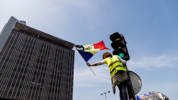 A yellow vest protester waves a French national flag on International Workers' Day in the Montparnasse district of Paris, France, on Wednesday, May 1, 2019. French President Emmanuel Macron has called for an extremely firm response to violent protesters at Wednesday's traditional May 1 holiday demonstrations. 