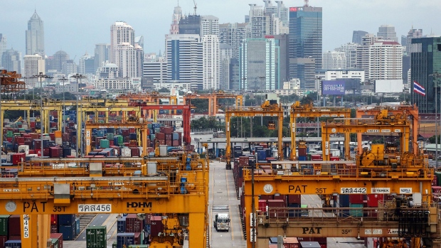 Containers sit stacked near gantry cranes at the Port of Bangkok as high rise buildings stand in the background at night in Bangkok, Thailand, on Wednesday, Sept. 23, 2015. The Bank of Thailand is scheduled to release its quarterly gross domestic product (GDP) on Sept. 25. 
