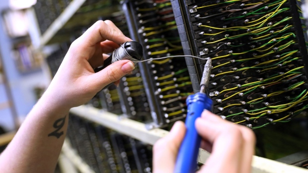 A network engineer from Openreach, a unit of BT Group Plc, connects jumper wires on a communications rack inside an exchange building in this arranged photograph in Upminster, U.K., on Thursday, Nov. 10, 2016. Regulator Ofcom called on BT, the U.K.'s former telecommunications monopoly, to set up a legally separate entity for the Openreach network unit within BT, with its own board, but stopped short of seeking a breakup. 