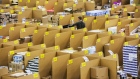 An employee moves between stacked boxes and parcels ahead of shipping from the warehouse of an Amazon.com Inc. fulfillment center in Koblenz, Germany. 