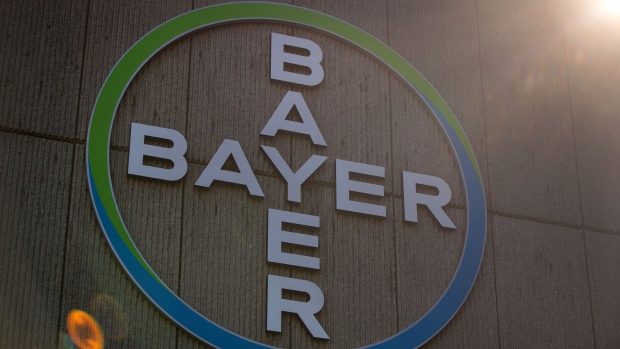 The Bayer AG logo sits on display behind silhouetted members of the management board during the company's annual general meeting in Bonn, Germany, on Friday, May 25, 2018. “We anticipate being able to close the acquisition of Monsanto in the near future,” Bayer Chief Executive Officer Werner Baumann said in statement ahead of the meeting. 