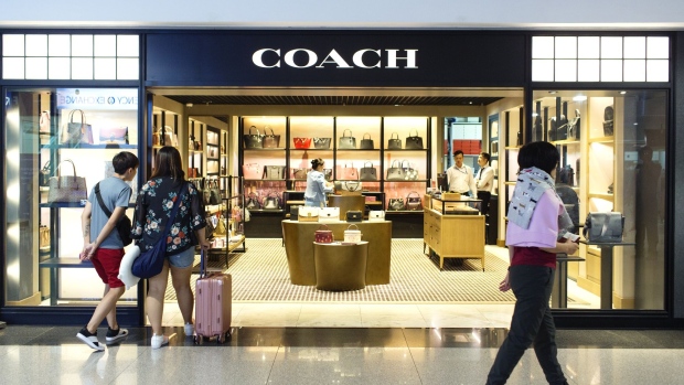 Travelers walk past a Coach Inc. store at the Tan Son Nhat International Airport in Ho Chi Minh City, Vietnam, on Saturday, Dec. 22, 2018. Vietnam's Civil Aviation Authority estimates that the nation's airports handled 106 million passengers in 2018, a 12.9 percent increase year on year, according to a statement released on Dec. 12. 