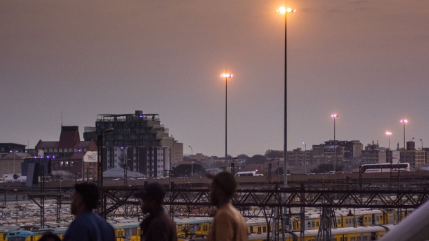 Pedestrians walk across Nelson Mandela bridge as night falls in the central business district of Johannesburg, South Africa, on Tuesday, Aug. 8, 2019. Eskom Holdings SOC Ltd., South Africa’s biggest polluter, said emissions of particulate matter that cause chronic respiratory disease are at their highest level in two decades as the state power utility’s financial meltdown has seen it skip maintenance and has triggered strikes. 