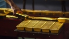 A worker lifts a gold bullion bar from a conveyor machine at the Rand Refinery Ltd. plant in Germiston, South Africa, on Wednesday, Aug. 16. 2017. Established by the Chamber of Mines of South Africa in 1920, Rand Refinery is the largest integrated single-site precious metals refining and smelting complex in the world, according to their website. 