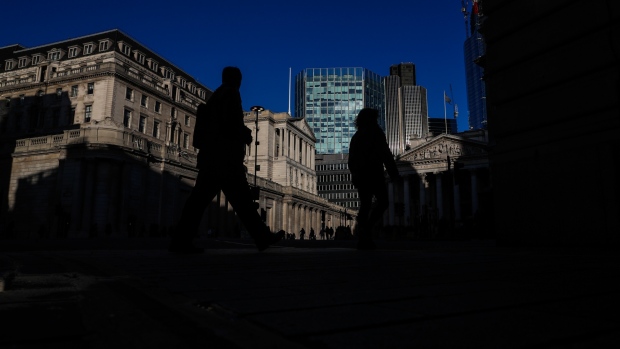 Pedestrians cross the street in view of the Bank of England (BOE) in the City of London, U.K., on Thursday, Feb. 7, 2019. The BOE warned that damage to the economy from Brexit has increased as it cut its growth forecast and predicted a dramatic slump in investment. 