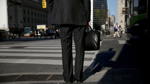 A pedestrian waits to cross a street in the financial district of Toronto. 