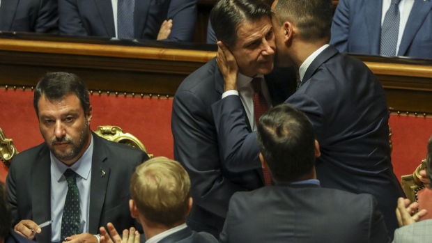 Luigi di Maio, Italy's deputy prime minister, right, embraces Giuseppe Conte, Italy's prime minister, center, as Matteo Salvini, Italy's deputy prime minister, left, looks on following Conte's address to the Senate in Rome on Aug. 20, 2019. 