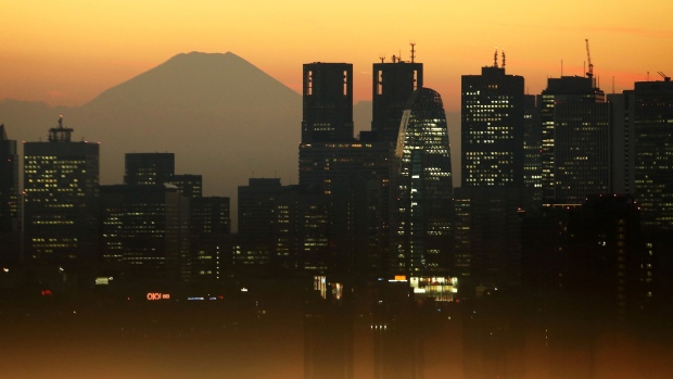 Mount Fuji stands beyond buildings as a visitor looks out at the skyline from an observation deck in Tokyo, Japan, on Friday, Jan. 11, 2019.
