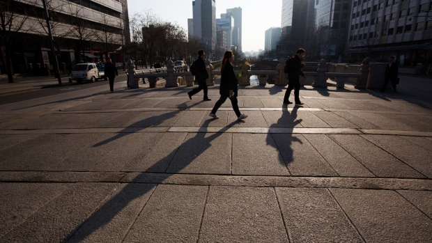 Pedestrians cast shadows as they cross a bridge at the Cheonggye Stream in Seoul, South Korea, on Monday, March 13, 2017. South Korea is turning to a daunting yet familiar task in the aftermath of former President Park Geun-hye's ouster: Rooting out corruption among political and business leaders. 