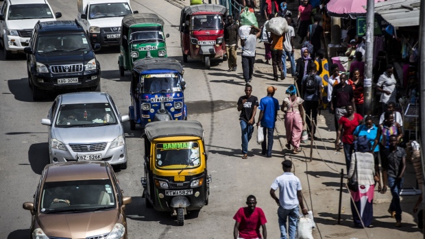 Automobiles and tuk-tuk drivers travel alongside pedestrians in Mombasa, Kenya. 