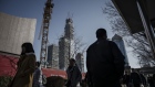 Pedestrians walk past a construction crane in downtown Beijing. 