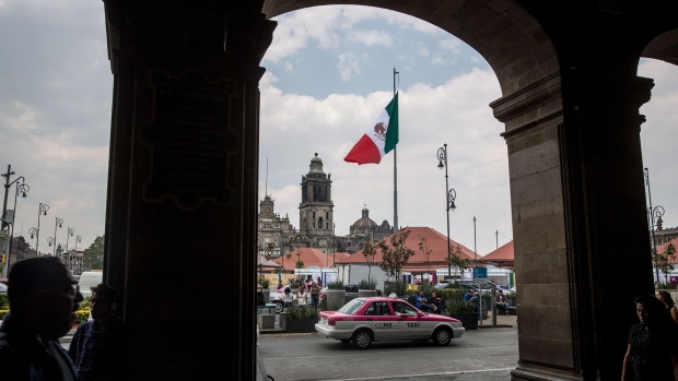 A taxi cab passes in front of the Mexican flag flying at the Plaza de la Constitucion (Zocalo) in Mexico City. 