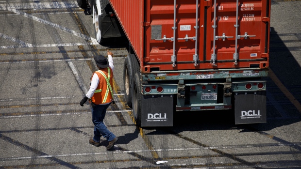 A worker checks a semi-truck chassis at the APM shipping terminal in the Port of Los Angeles in Los Angeles, California, U.S., on Tuesday, May 7, 2019. The terminal is planning to replace diesel trucks and human workers. It has already ordered an electric, automated carrier from Finnish manufacturer Kalmar, part of the Cargotec Corp., that can fulfill the functions of three kinds of manned diesel vehicles: a crane, top-loader and truck. 