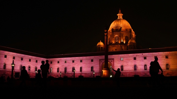 People are silhouetted as the North Block of the Central Secretariat buildings, which houses the Ministries of Finance and Home Affairs, stands illuminated at night in New Delhi, India, on Sunday, Jan. 28, 2018. With India's Finance Minister Arun Jaitley readying to deliver his annual budget on Feb. 1, traders are seeking to hedge a rally that has added more than $425 billion in equity values in the past four months. 