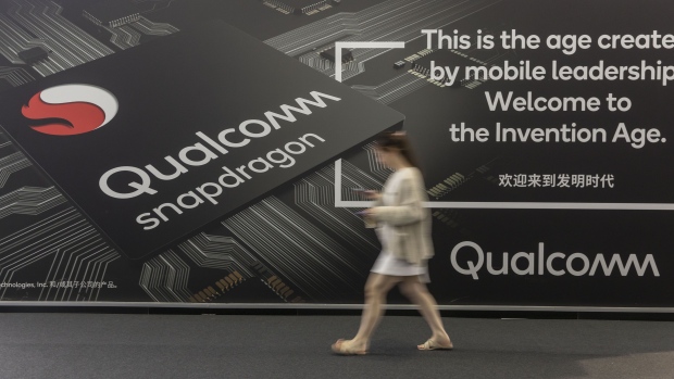 An attendee walks past an advertisement for Qualcomm Inc.'s Snapdragon processors at the MWC Shanghai exhibition in Shanghai, China, on Thursday, June 27, 2019. The Shanghai event is modeled after a bigger annual industry show in Barcelona. 