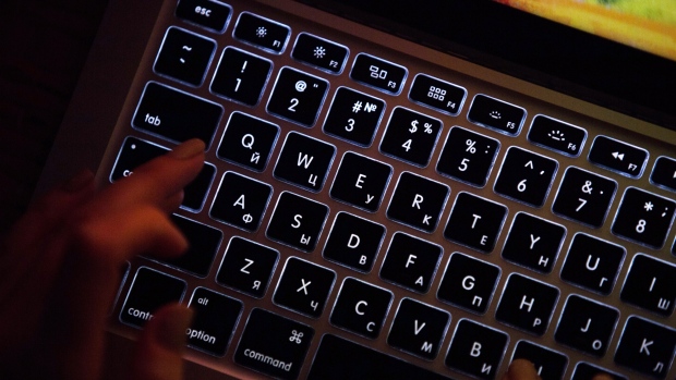 A person uses a laptop computer with illuminated English and Russian Cyrillic character keys in this arranged photograph in Moscow, Russia, on Thursday, March 14, 2019. Russian internet trolls appear to be shifting strategy in their efforts to disrupt the 2020 U.S. elections, promoting politically divisive messages through phony social media accounts instead of creating propaganda themselves, cybersecurity experts say. 