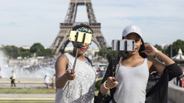 GETTY - Tourists take a selfie using a selfie stick in front of the Eiffel Tower