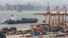 A container ship passes in front of containers and gantry cranes at the Haitian Container Terminal, operated by the Xiamen Port Authority, in Xiamen, China, on Monday, Aug. 26, 2019. 